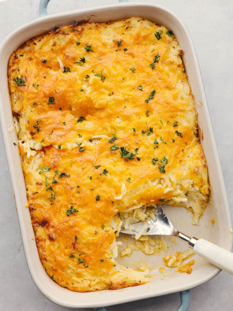 Hashbrown casserole is the ultimate cheesy comfort food! This creamy, hearty dish is perfect for potlucks, parties, and to serve as a side! Top-down photo of hashbrown casserole in a white serving dish.