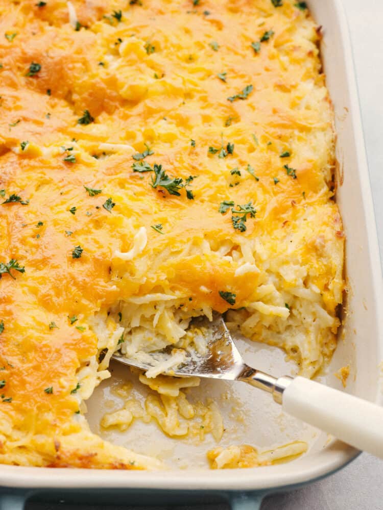 Hashbrown casserole is the ultimate cheesy comfort food! This creamy, hearty dish is perfect for potlucks, parties, and to serve as a side! Closeup of a hashbrown casserole with a slice taken out of it.