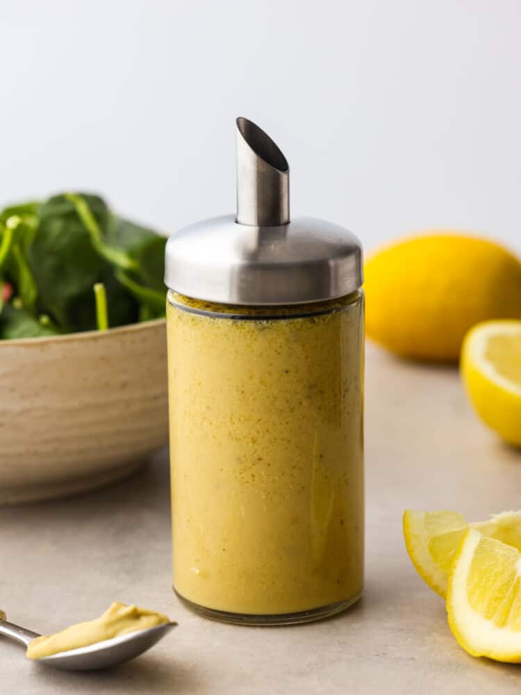 Homemade honey mustard dressing will give any salad the best boost of sweet and tangy flavor. You only need a handful of simple ingredients to whip it up. Once you've made it yourself, you won't want it any other way! Homemade honey mustard dressing in a glass container with a metal spout.