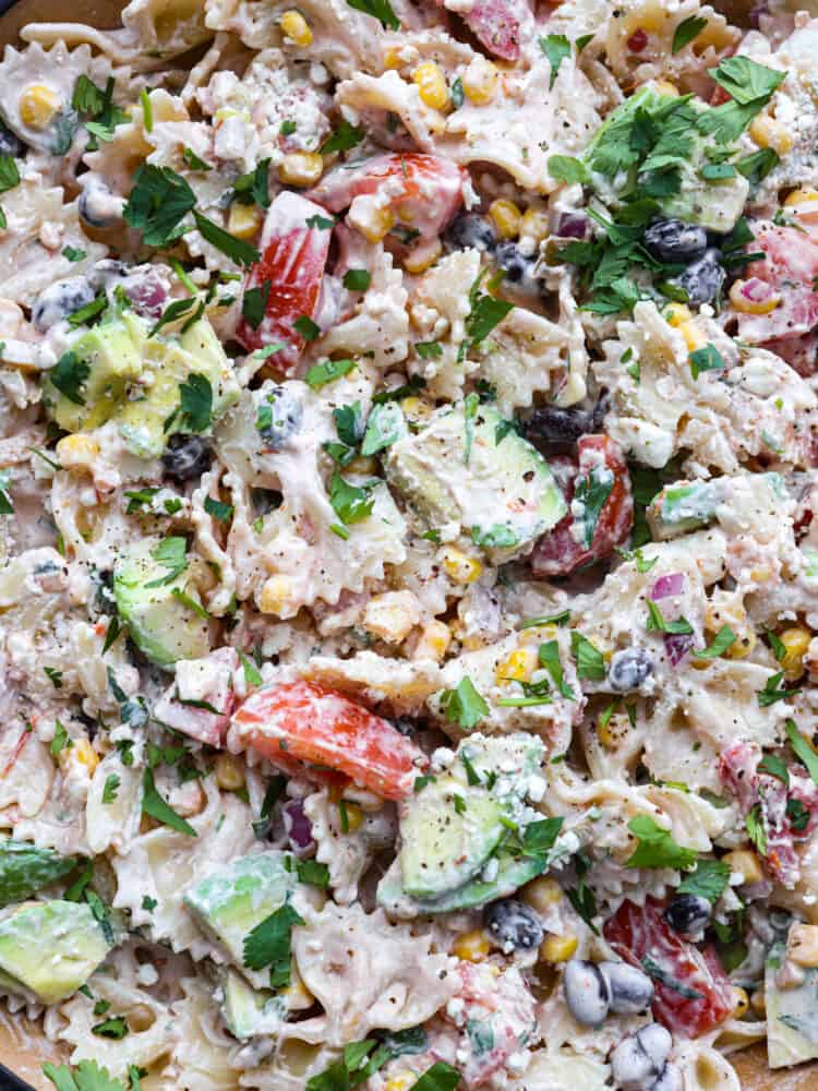 pasta salad is an unbelievably easy and flavorful pasta salad filled with colorful ingredients like black beans, tomatoes, and corn.ย With a creamy dressing and spices from onion, cilantro, and cumin, this delicious pasta salad will be the hit of your summer barbecues for sure A close up of Mexican pasta salad.