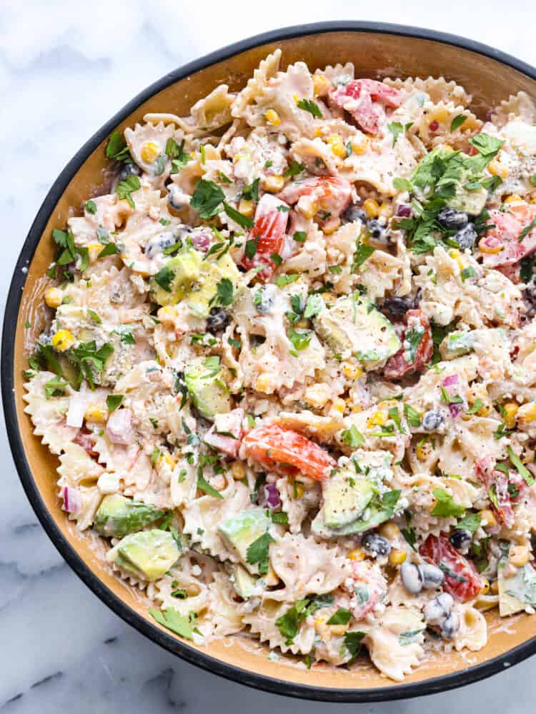 pasta salad is an unbelievably easy and flavorful pasta salad filled with colorful ingredients like black beans, tomatoes, and corn.ย With a creamy dressing and spices from onion, cilantro, and cumin, this delicious pasta salad will be the hit of your summer barbecues for sure The top view of Mexican pasta salad.