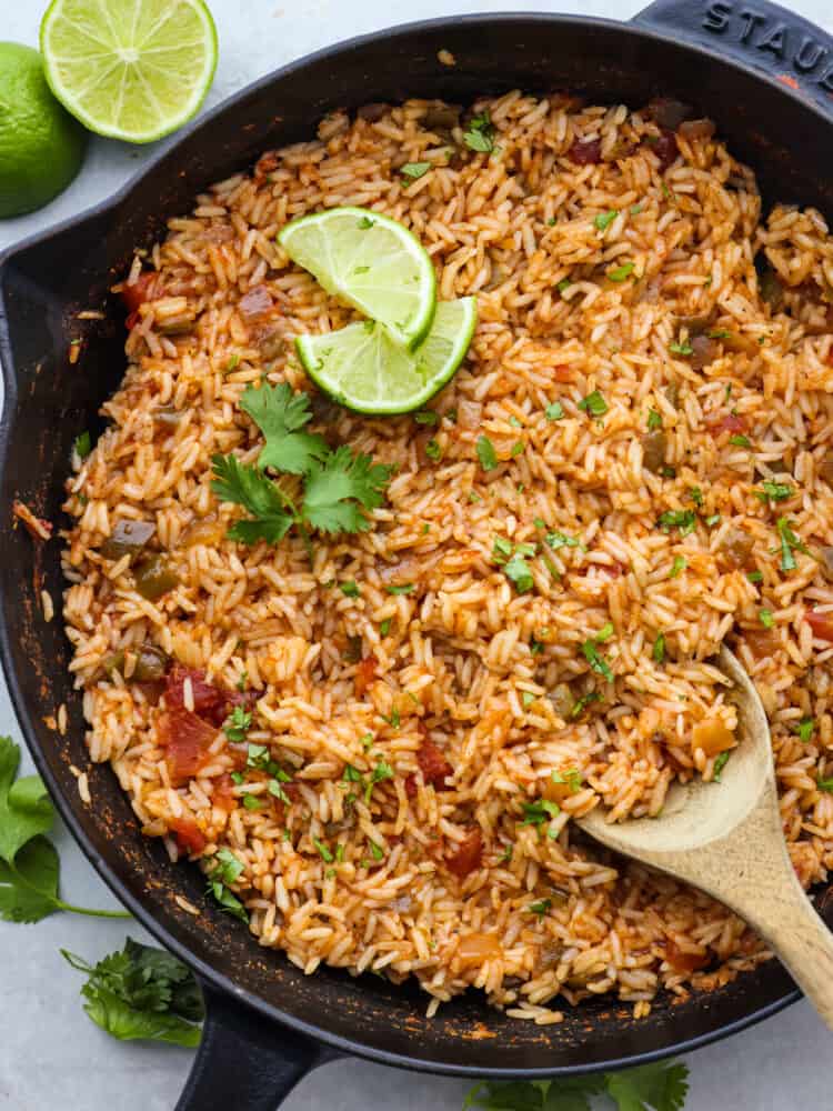 This Mexican rice is so easy to make! Simmered until tender in broth, salsa, and a mix of spices gives it a ton of flavor, perfect for adding to any fiesta. The top view of a pan full of cooked Mexican rice.