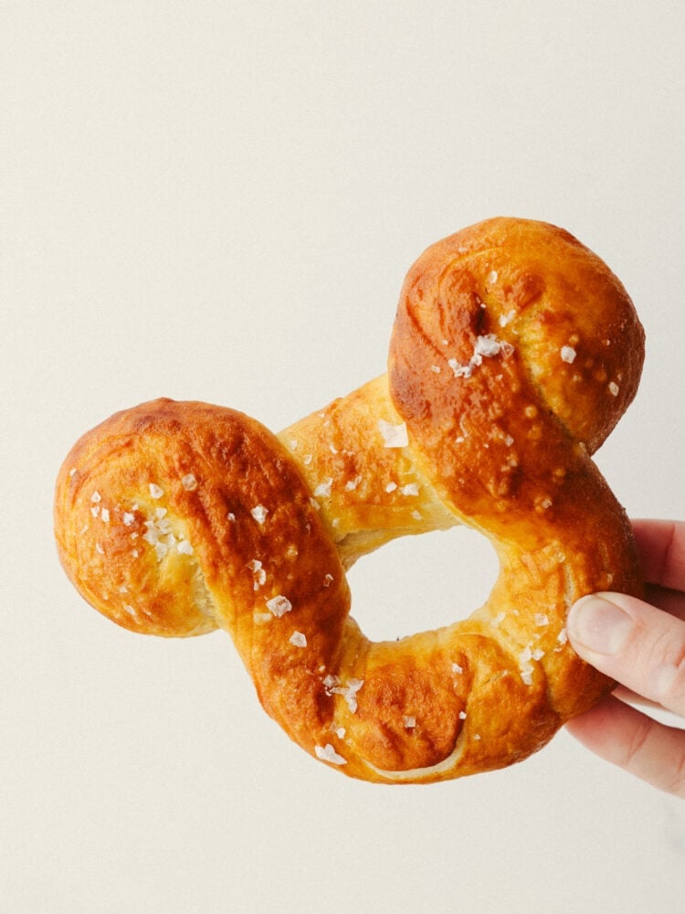 Disney fans, these pretzels are for you! They are golden brown on the outside, have a soft texture on the inside, and are topped with coarse salt. And, they are shaped like Mickey! A soft pretzel doesn't get much better than that! A closeup of a hand holding a Mickey pretzel.