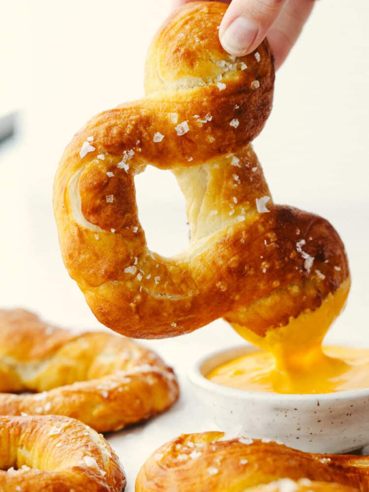 Disney fans, these pretzels are for you! They are golden brown on the outside, have a soft texture on the inside, and are topped with coarse salt. And, they are shaped like Mickey! A soft pretzel doesn't get much better than that! A Mickey pretzel being dipped into cheese sauce.