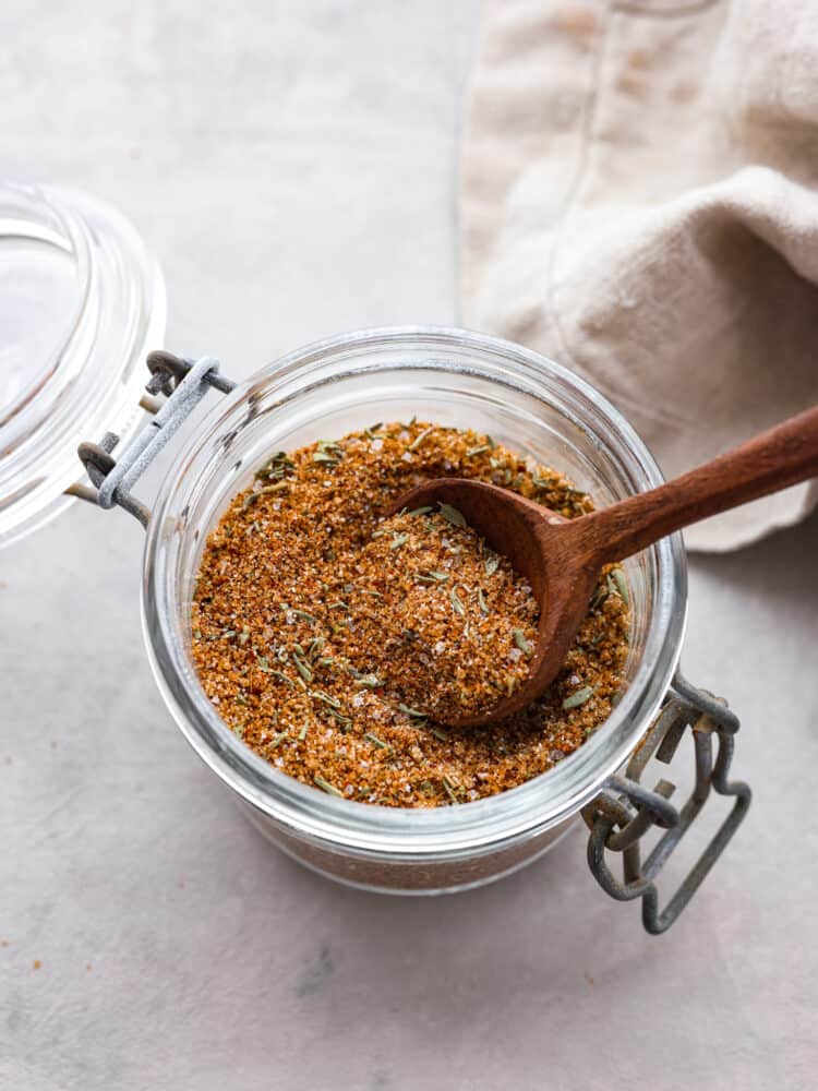This pork seasoning is the perfect bled of delicious spices. It only takes about 5 minutes to whip up and will elevate your meals for months to come! Pork seasoning in a small jar with a wooden spoon.
