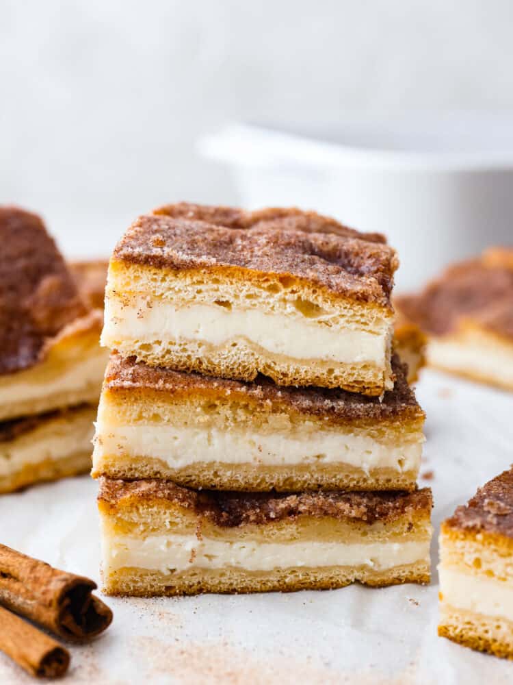 These sopapilla cheesecake bars have the most delicious flakey, cinnamon sugar crust on the top and the bottom. Sandwiched in between is a creamy cheesecake filling that everyone will go crazy over! A stack of sopapilla cheesecake bars.