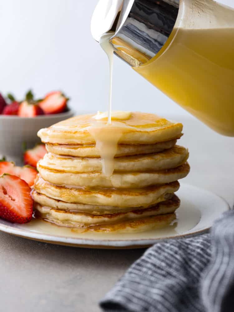 Coconut syrup is going to be your new favorite breakfast addition! Itโs creamy, sweet, and will coat pancakes and waffles in delicious, nutty flavor. Pouring coconut syrup over a stack of pancakes.