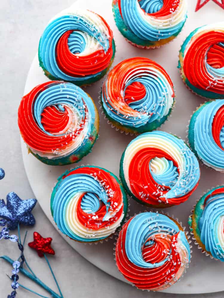 These festive red, white and blue cupcakes are perfect for celebrating the 4th of July this year! They are tender, moist, and swirled with all the colors perfect for celebrating! The top view of red, white and blue cupcakes on a marble platter.
