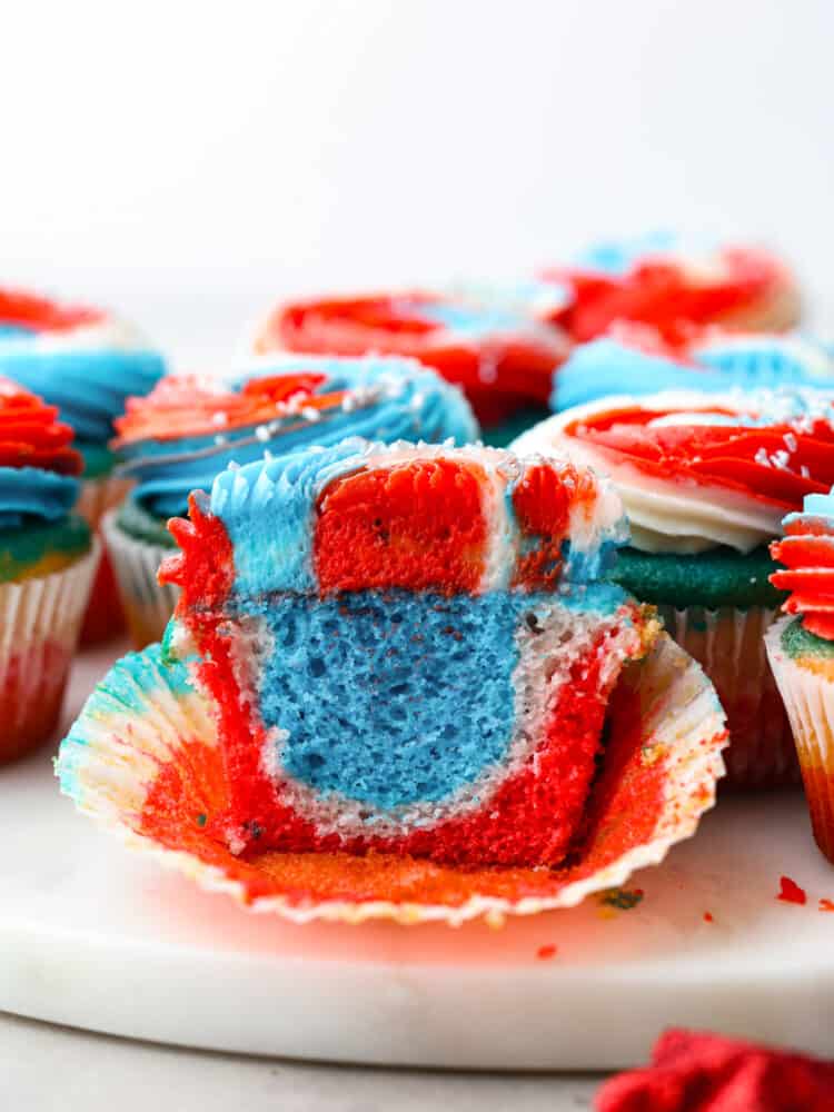 These festive red, white and blue cupcakes are perfect for celebrating the 4th of July this year! They are tender, moist, and swirled with all the colors perfect for celebrating! The side view of a red, white and blue cupcake cut open so that you can swee the swirled colors inside.
