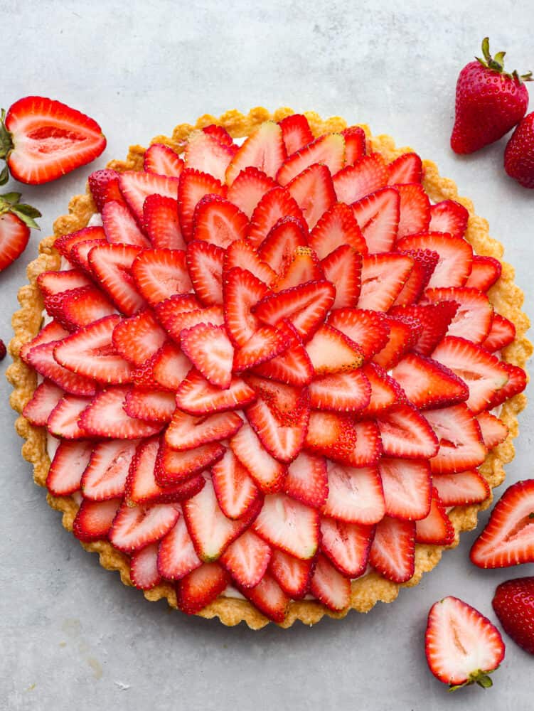 A perfectly summery strawberry tart made with a buttery crust, smooth cream cheese-based filling, and fresh summer berries! Each bite is filled with creamy, juicy flavor that you won't be able to get enough of! Top-down view of a whole strawberry tart.