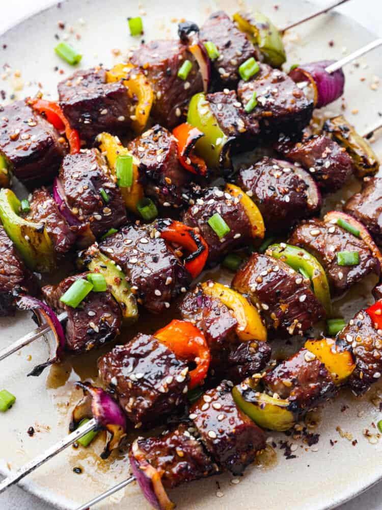 Grilled Asian Garlic Steak Skewers are marinated in a delicious Asian garlic sesame sauce and grilled to tender and juicy perfection!ย A fun and unique addition to any gathering! Asian garlic steak skewers on a platter, ready to eat.