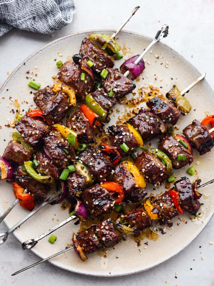 Grilled Asian Garlic Steak Skewers are marinated in a delicious Asian garlic sesame sauce and grilled to tender and juicy perfection. ย A fun and unique addition to any gathering! Asian Grilled Garlic Steak Skewers cooked and on a plate.