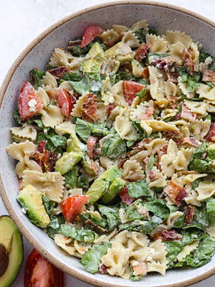 BLT Avocado Pasta Salad is fresh and crisp romaine lettuce tossed in bacon, tomato, pasta, and avocado. Topped with a creamy dressing and sprinkled with feta cheese this is one amazing salad! The top view of a bowl of BLT avocado pasta salad.