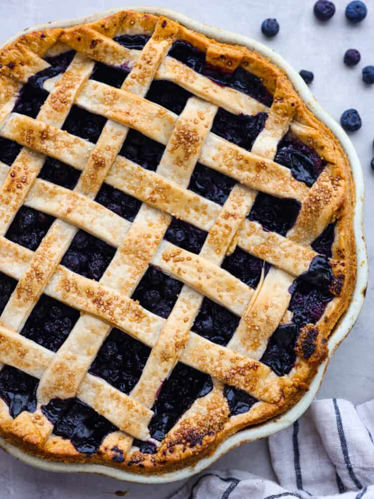 This classic blueberry pie is a fresh and delicious dessert that's made for summertime! Filled with blueberries and topped with the most delicious and beautiful lattice crust, this pie is sure to impress any guest. The topview of a blueberry lattice pie.