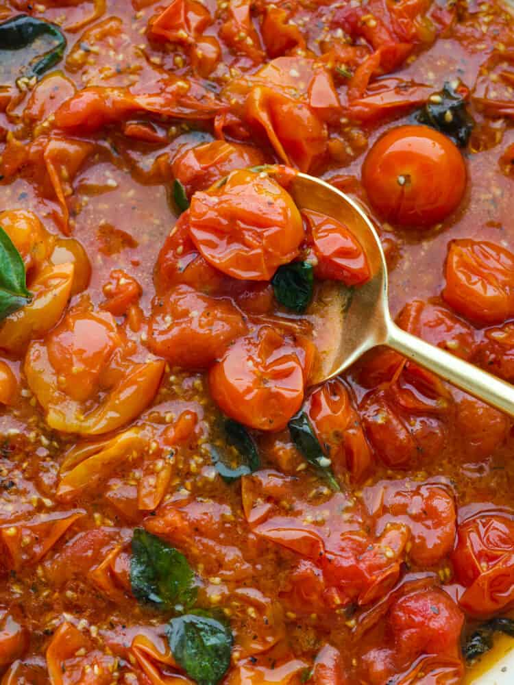 With just a few ingredients you can easily make tomato sauce using cherry tomatoes. Cherry tomatoes infused with fresh garlic and Italian seasonings make this cherry tomato sauce perfect for pasta, on top of roasted vegetables, or with a side of artisan bread. Close view of cherry tomato sauce with a gold spoon lifting up the sauce.