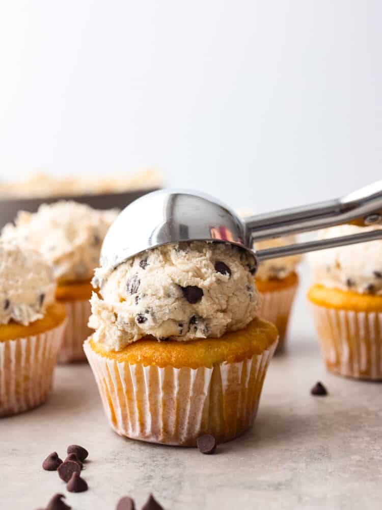 This scrumptious frosting is as sweet and irresistible as cookie dough! Add it to your favorite desserts for a pop of creamy decadence! Adding a scoop of cookie dough frosting to a cupcake.