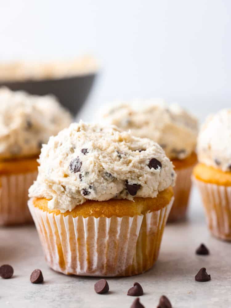 This scrumptious frosting is as sweet and irresistible as cookie dough! Add it to your favorite desserts for a pop of creamy decadence! Closeup of a cupcake topped with cookie dough frosting.