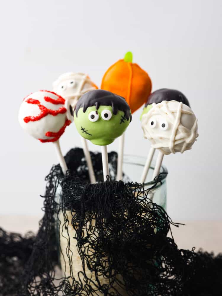 These easy, festive, and adorable Halloween donut hole pops will thrill your guests! Believe me when I say people can't stop talking about how adorable, and how delicious these pops are. You'll be so glad you served these at your Halloween party this year. 5 donut hole pops decorated like Halloween characters in a glass jar.