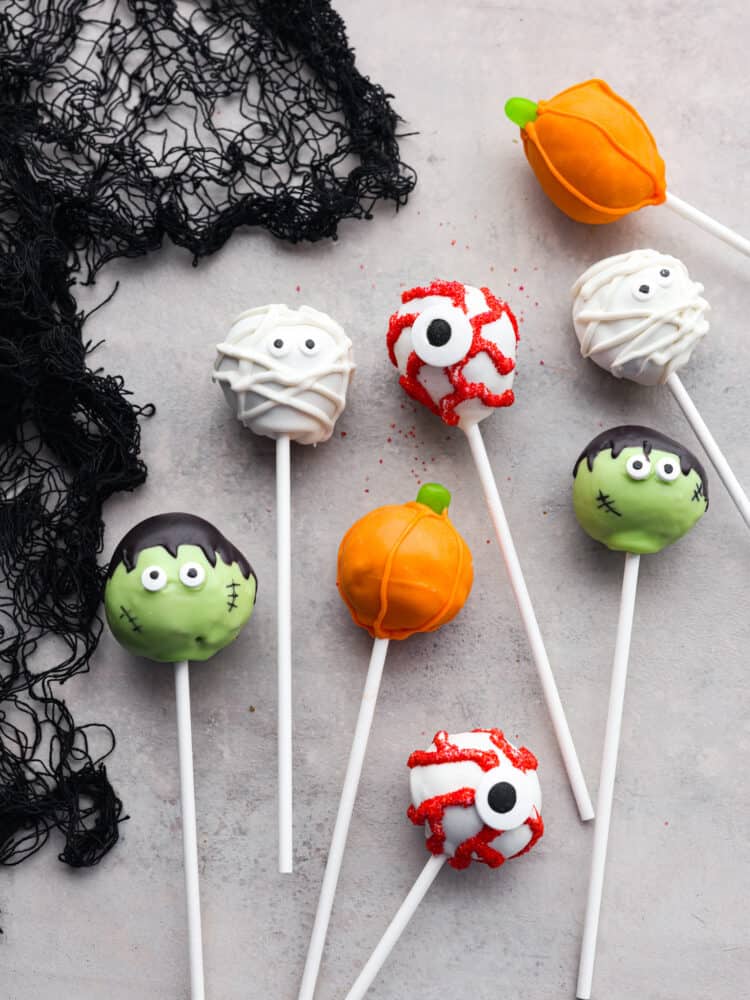 These easy, festive, and adorable Halloween donut hole pops will thrill your guests! Believe me when I say people can't stop talking about how adorable, and how delicious these pops are. You'll be so glad you served these at your Halloween party this year. Top-down view of donut hole pops decorated like various Halloween characters.