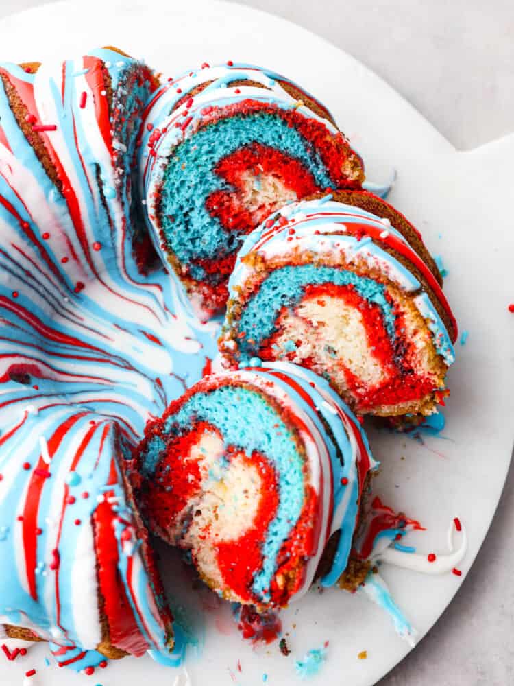 This firework bundt cake is exploding with colors and flavor! It not only looks impressive but it tastes so delicious that you will definitely be making this for every Fourth of July! The top view of a firework bundt cake with a few pieces slices so that you can see the marbles red white and blue inside.