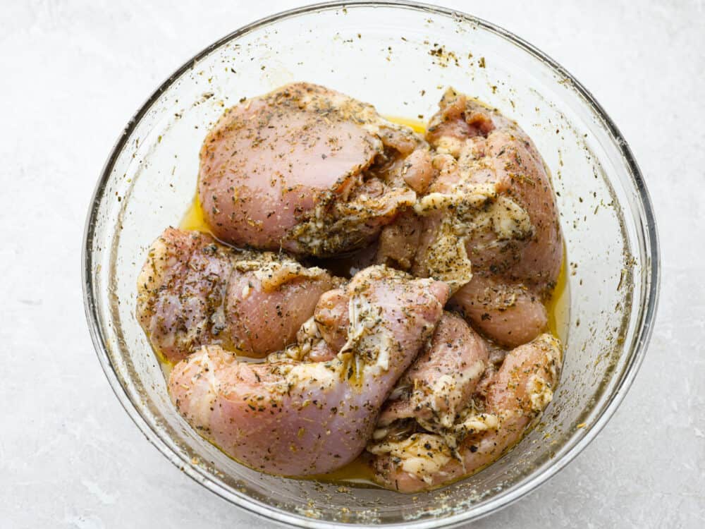 This easy grilled lemon chicken recipe just requires a few ingredients and grills up in just a few minutes! It's tender and juicy and packed with lots of fresh flavors! A glass bowl of raw chicken covered iin a lemon marinade.