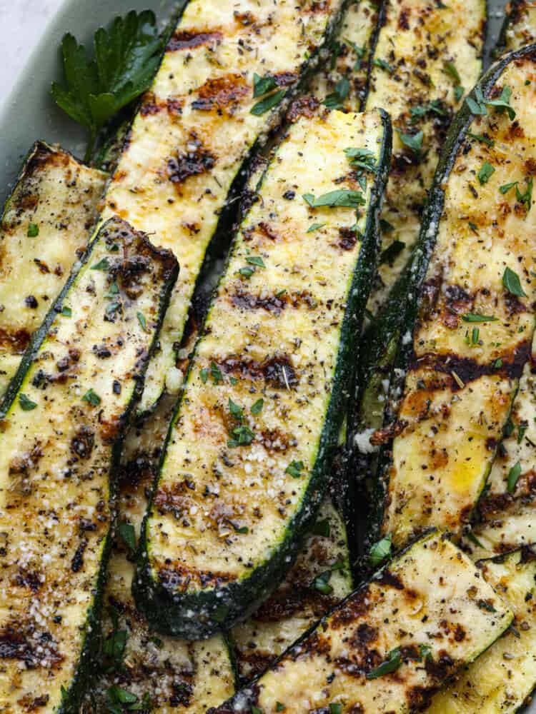 If you're not making zucchini bread with all of that home-grown zucchini, then you HAVE to try this grilled zucchini! Light, smoky, and perfectly seasoned, it cooks up in minutes and goes with just about everything. A closeup of grilled zucchini spears.