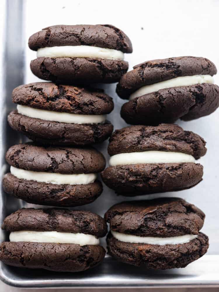 Get ready to enjoy the best homemade cookie out there! These homemade cakesters are perfectly soft on the outside and filled with the BEST creamy, oreo filling. You won't be able to stop at just one! The side view of seven oreo cakesters on a cookie sheet.