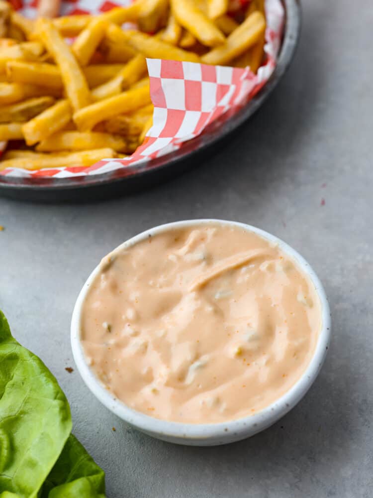The famous In-N-Out spread is the best part of the burgers and fries at the popular west coast restaurant. Now you can enjoy this sweet and tangy condiment at home with this copycat recipe for In-N-Out spread. Overhead photo of In-N-Out sauce in a bowl with a side of fries and lettuce from a hamburger next to the bowl of sauce.