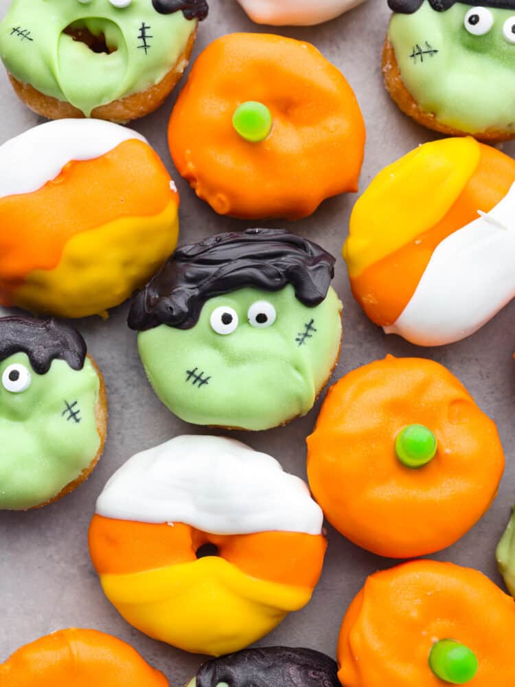If you are looking for simple and easy instructions on decorating mini Halloween donuts, then you are in luck! Candy corns, pumpkins, and Frankenstein will grace the presence of your Halloween party this year with these decorated donuts! A close up shot o mini Halloween donuts.