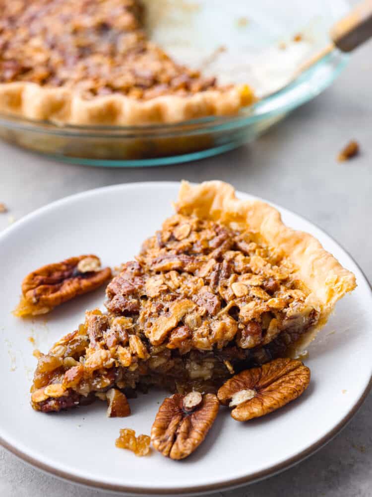 If you love pies, then this delicious and unique oatmeal pecan pie is for you! And if you haven't made a pie before, do not fear... this recipe really is so easy! A slice of oatmeal pecan pie on a white plate.