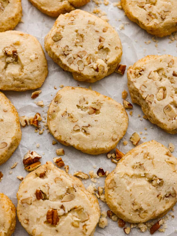 These pecan shortbread cookies are insanely delicious! They melt in your mouth with their fall-apart texture and sweet taste. The added texture of a crunchy pecan makes these practically perfect! The top view of baked cookies on parchment paper.