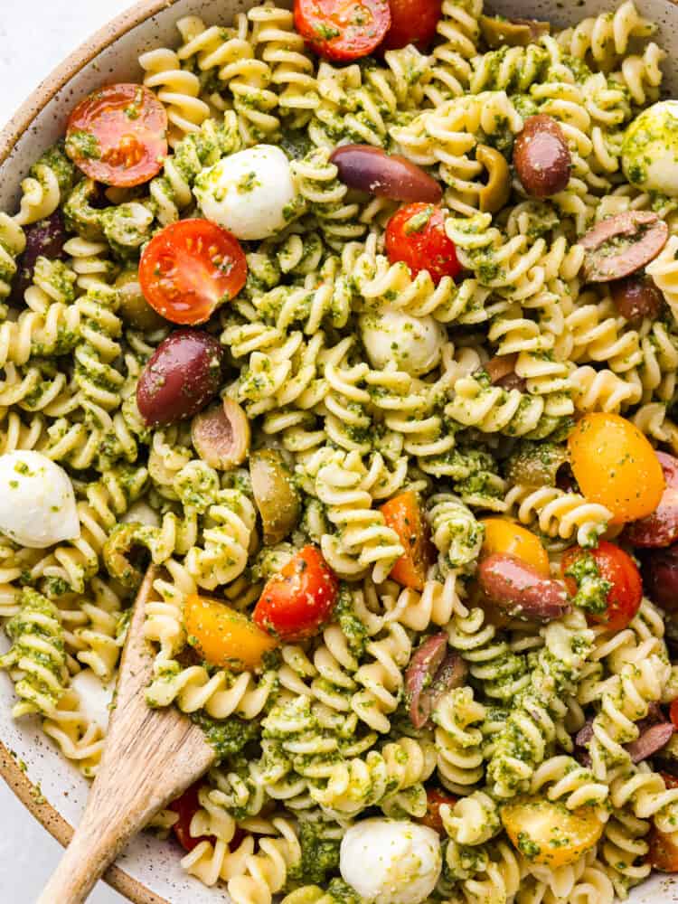 This pesto pasta salad is loaded up with fresh mozzarella, and juicy tomatoes, coated with an easy-to-make homemade pesto sauce made with fresh basil and garlic. It's so fresh and delicious! A zoomed in shot of the top of pesto pasta salad.