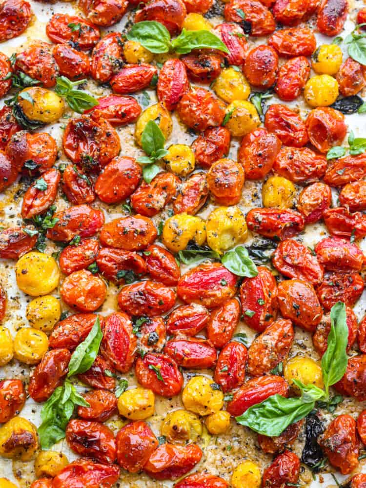 These roasted cherry tomatoes are seasoned with garlic and basil and literally bursting to perfection. It's a simple and delicious side dish that you will want to pair with every meal! The top view of roasted cherry tomatoes on a baking sheet.