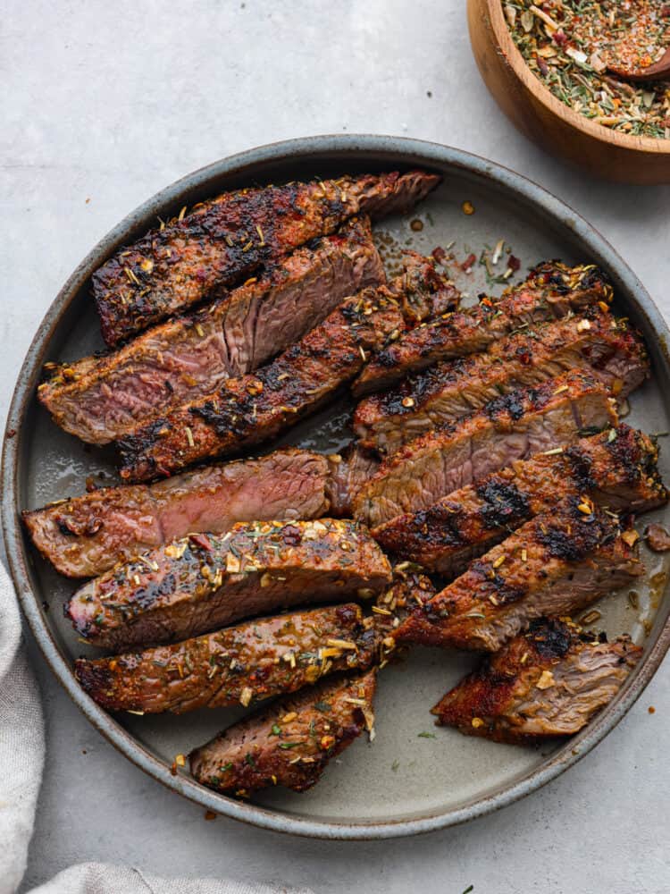 Get ready to add the most delicious flavor to your meat with this amazing steak seasoning! It packs a punch of flavor with garlic, onion, and herbs and will elevate any steak you cook! Cooked steak on a plate sliced and seasoned and ready to eat.