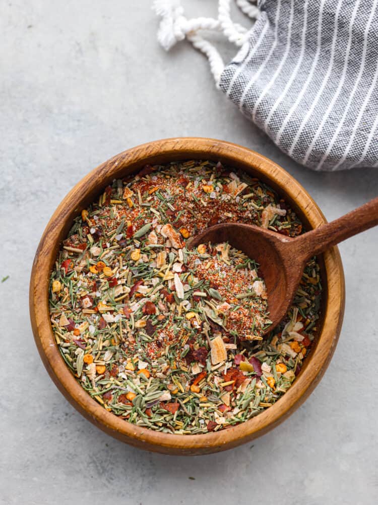 Get ready to add the most delicious flavor to your meat with this amazing steak seasoning! It packs a punch of flavor with garlic, onion, and herbs and will elevate any steak you cook! The top view of steak seasoning in a wooden bowl with a wooden spoon in it.