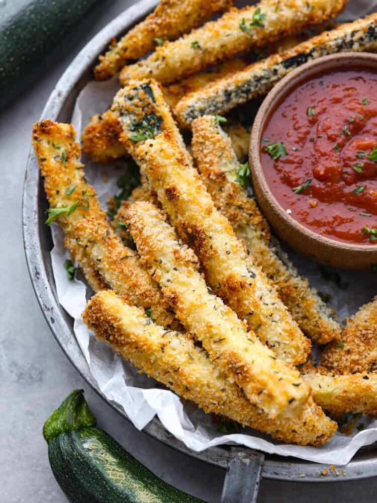 Baked zucchini fries are crispy on the outside with a crunchy, seasoned crust and tender zucchini inside. It's hard to stop after just one! Closeup shot of baked zucchini fries.