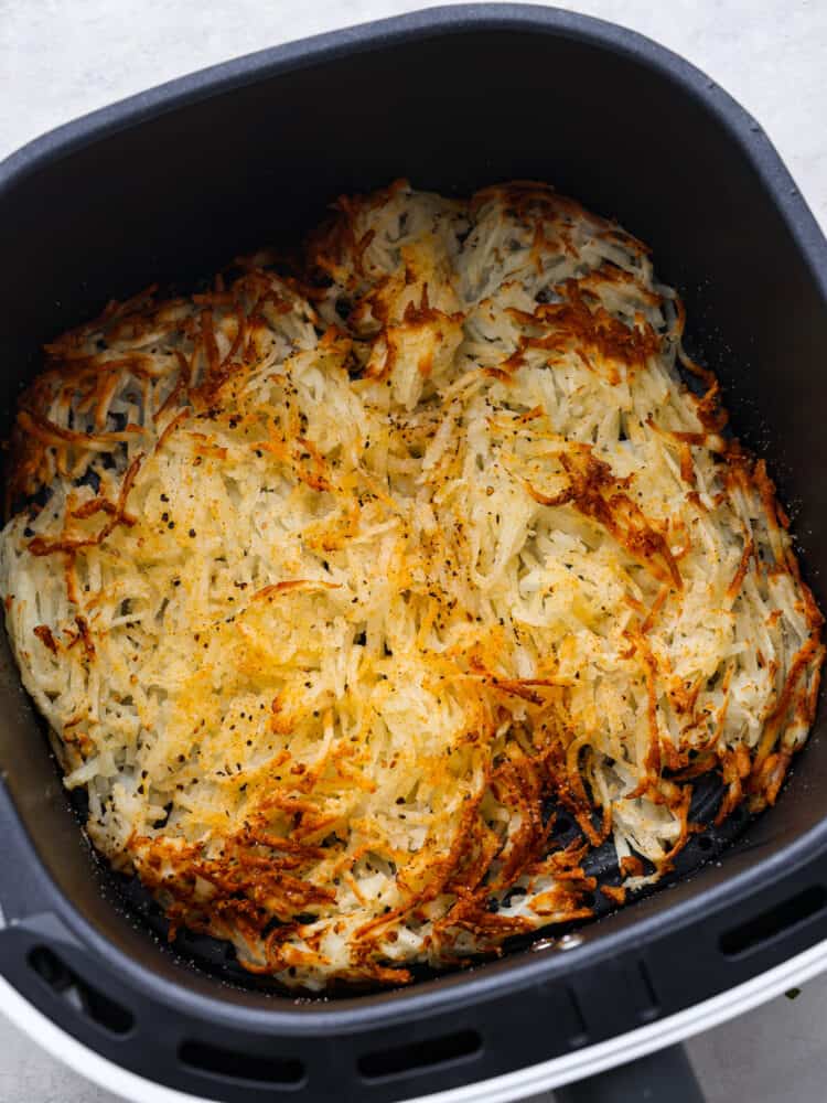 Make mornings easier with these air fryer hash browns cooked perfectly in minutes! Crispy, golden, and seasoned to taste like your favorite diner hash browns. Top view of cooked hash browns in the air fryer basket.
