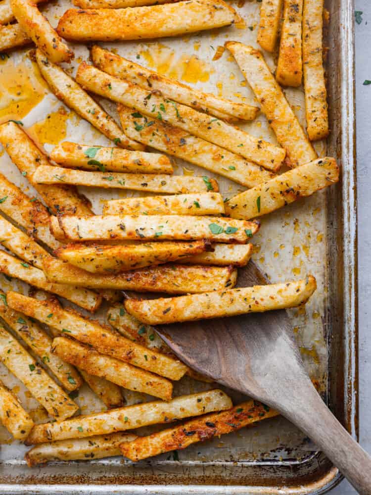 These delicious baked jicama fries are a low-carb alternative to French fries and are coated with savory seasonings! They're oven-roasted for that perfect crispy, golden brown outer layer. Top-down view of baked jicama fries on a baking sheet.