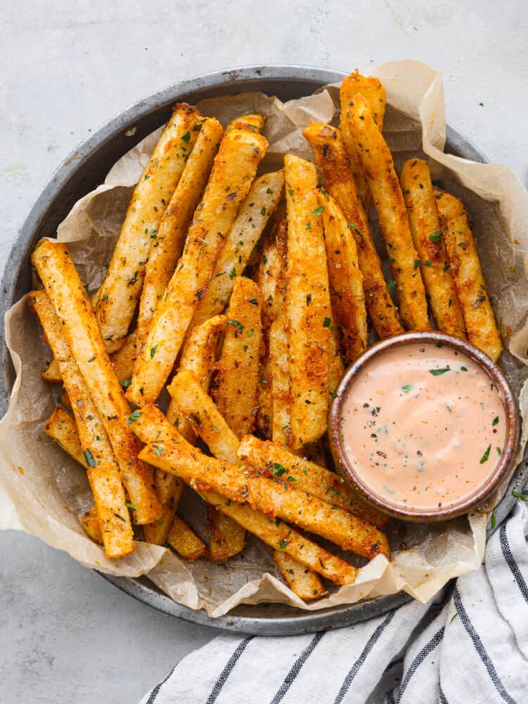 These delicious baked jicama fries are a low-carb alternative to French fries and are coated with savory seasonings! They're oven-roasted for that perfect crispy, golden brown outer layer. Top-down view of jicama fries served with fry sauce.