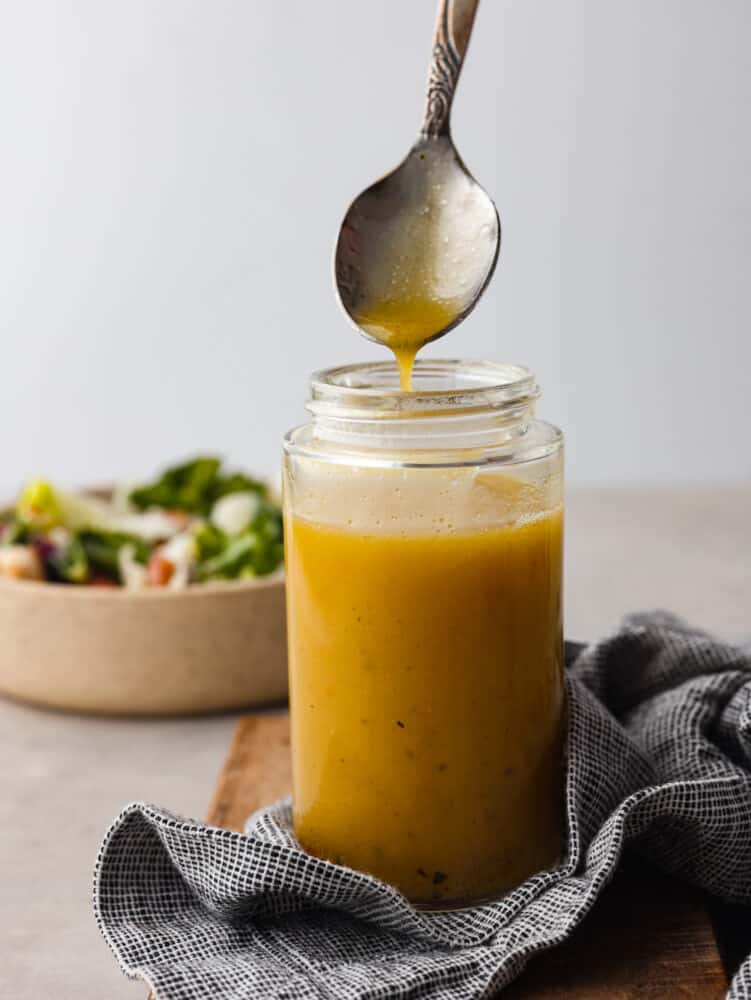 Apple cider vinaigrette is a staple dressing for adding a burst of bright, tangy flavor to your favorite salads. Make it from scratch and you won’t want it any other way! Apple cider vinaigrette in a glass jar.
