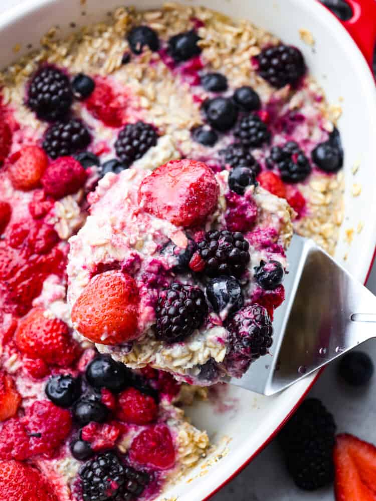 This baked berry oatmeal is a TikTok sensation that's every breakfast lover's dream! Warm, milky, and loaded with fresh berries, it's the most delicious way to start your day. Closeup of berry oatmeal being scooped up with a metal spatula.
