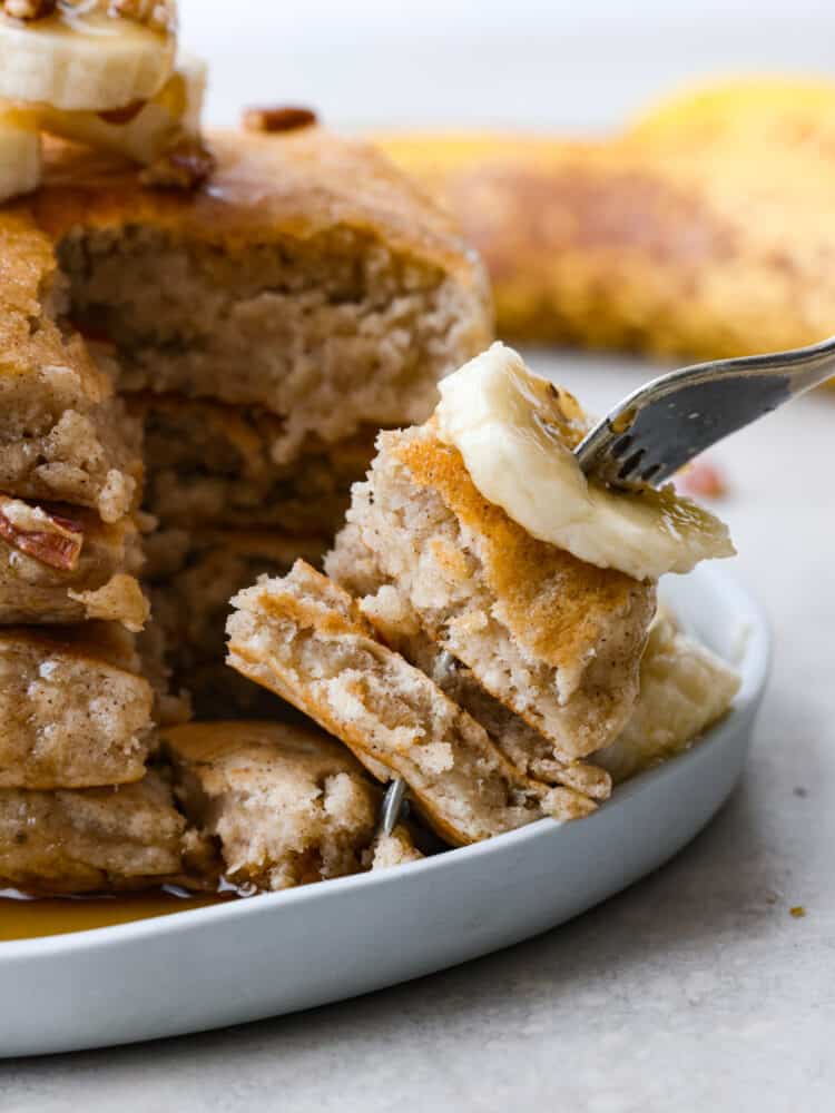 These banana pancakes are perfectly soft and fluffy and taste just like warm banana bread... in pancake form, of course! It's a great recipe to use when you have any over-ripe bananas! Banana pancakes on a plate with a fork cutting out a bite.