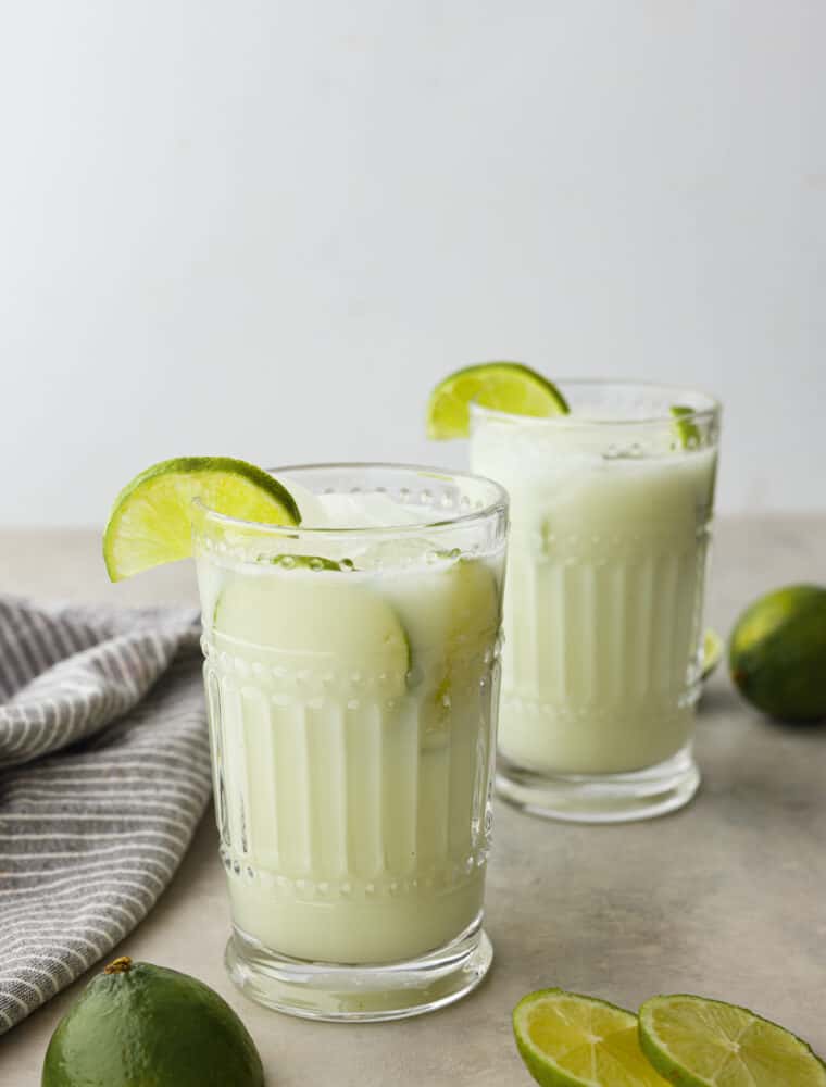 Brazilian lemonade is a 4-ingredient drink that is tangy, creamy, and refreshing! It’s the perfect mix of tart and sweet and will have your family hooked after first sip. 2 glasses of limeade topped with lime slices.