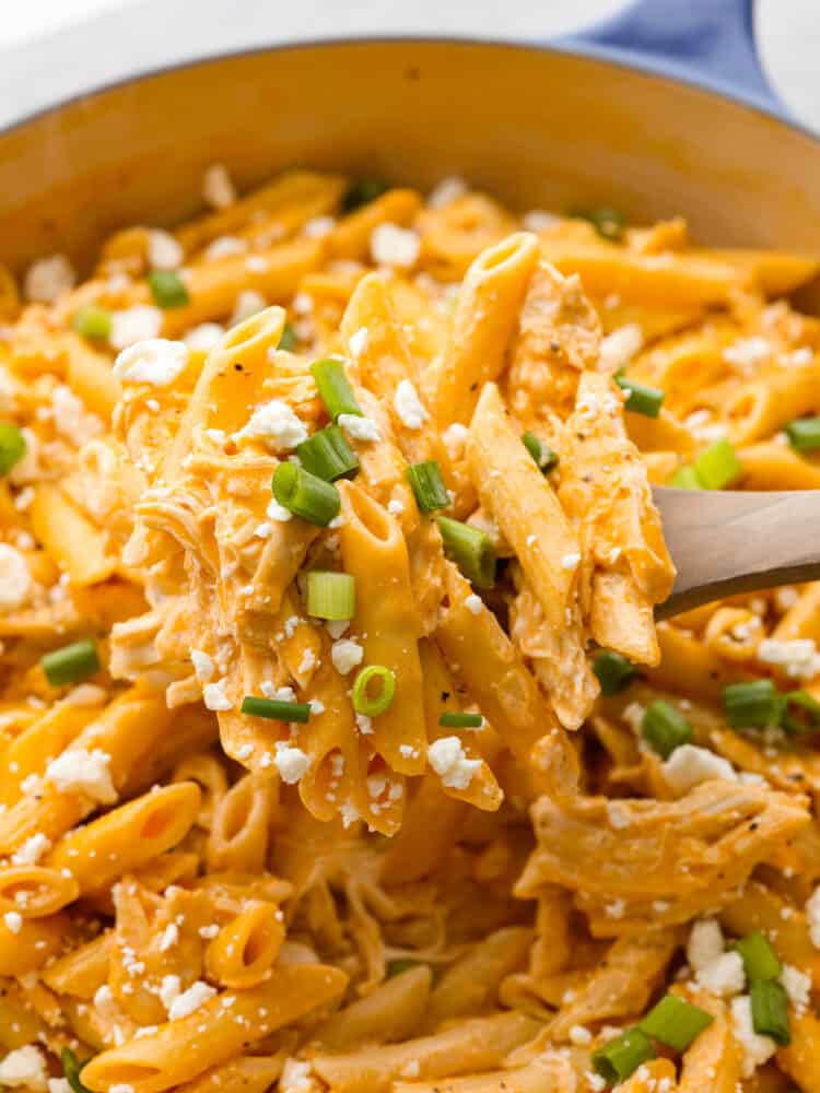 Get that classic buffalo flavor and combine it with some chicken and pasta, and you have yourself a mouthwatering entree that everyone will go crazy over! A closeup of a spoonful of buffalo chicken pasta on a wooden spoon.