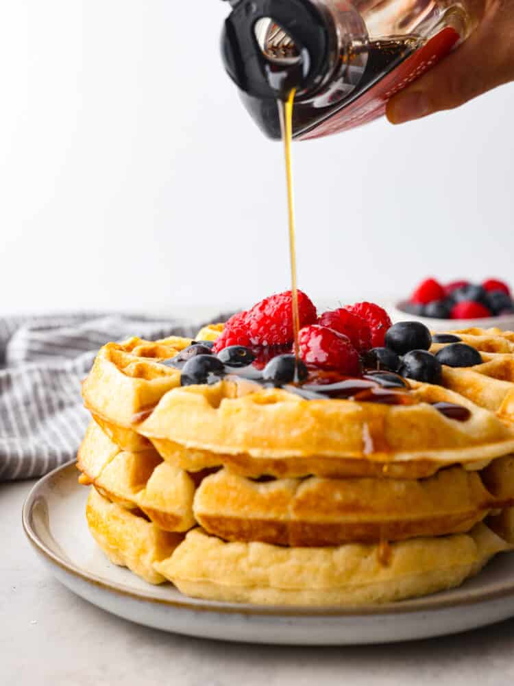 Buttermilk waffles are a classic breakfast recipe that is a family favorite! Fluffy and light on the inside with a crispy golden outside...buttermilk just makes everything better! Syrup being poured on 3 waffles stacked on top of each other.