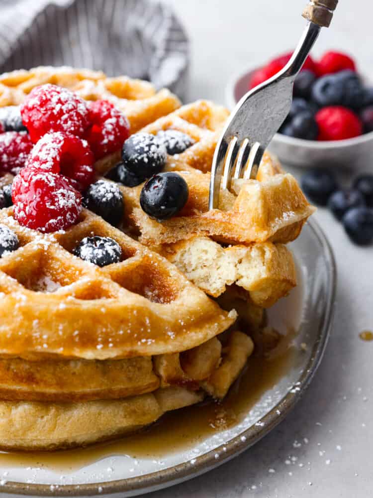 Buttermilk waffles are a classic breakfast recipe that is a family favorite! Fluffy and light on the inside with a crispy golden outside...buttermilk just makes everything better! Closeup of a stack of 3 waffles, topped with berries.