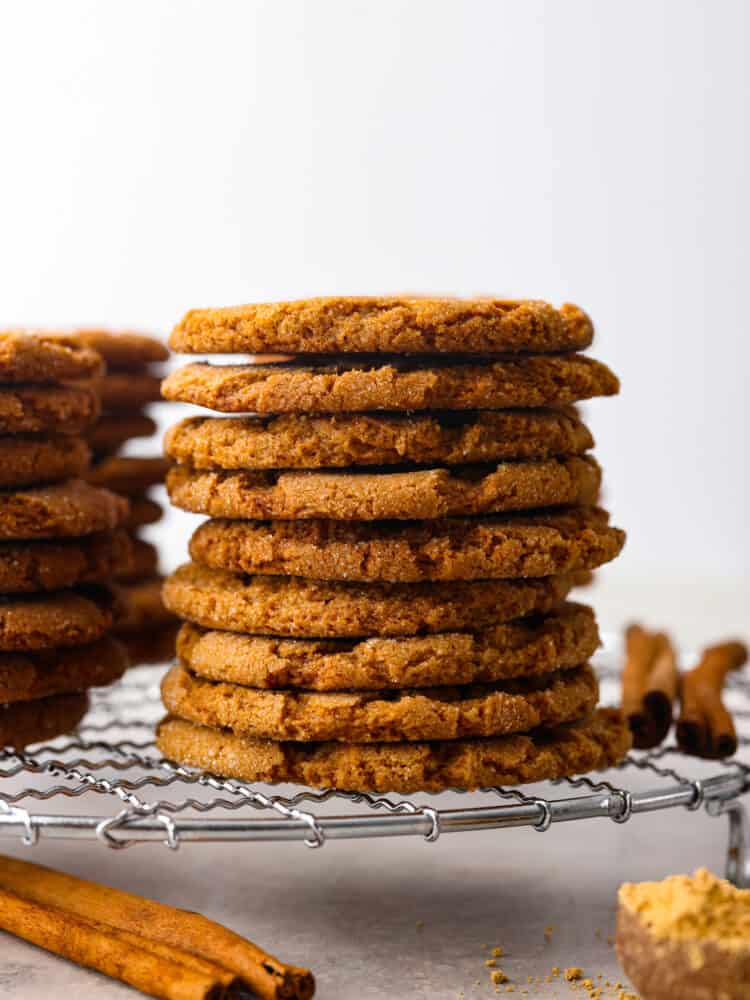 Crispy on the outside, warm and chewy on the inside, these Gingersnap Cookies are everything you want in a holiday dessert! They are the perfect way to finish off any holiday meal and leave everyone feeling merry and bright. Gingersnap cookies stacked on top of each other on a wire rack.