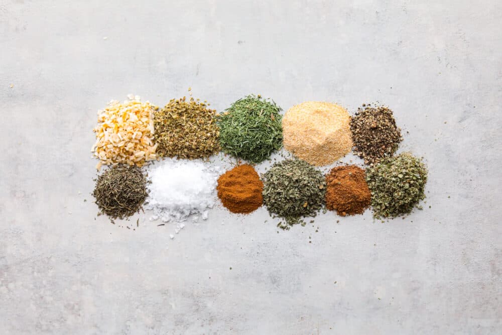 Using homemade Greek seasoning is the best way to add Mediterranean flair to your cooking! It mixes up in minutes and is perfect for adding delicious zesty flavor to all of your favorite meals. The various spices used in Greek seasoning measured and laid out on a flat surface.