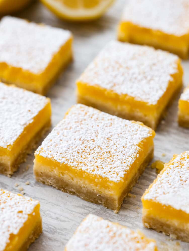 These are the most delicious and creamy lemon cheesecake bars. They have a buttery shortbread crust with a cheesecake and lemon layer and are dusted with powdered sugar. They are the perfect dessert! Lemon cheesecake bars cut into squares and sprinkled with powdered sugar.