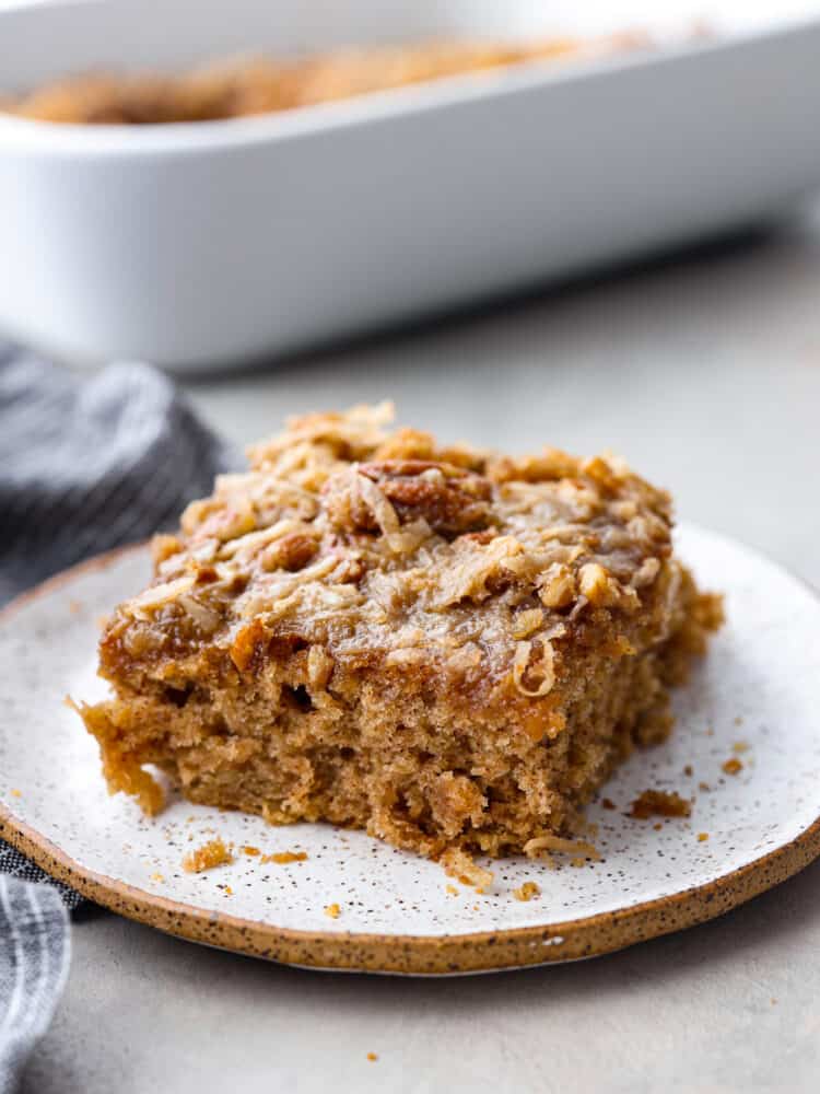 You have to make this oatmeal cake. Itโs an old-school recipe that doesnโt look like much, but that buttery pecan and coconut topping? Itโs gooey, crunchy, and totally addictive! Angle shot of a slice of oatmeal cake on a plate.